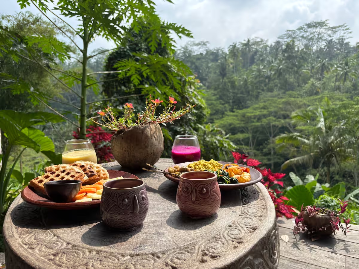 Vegan breakfast with waffles, fruit and juices on a terrace overlooking the jungle at Harmony Hill Bali