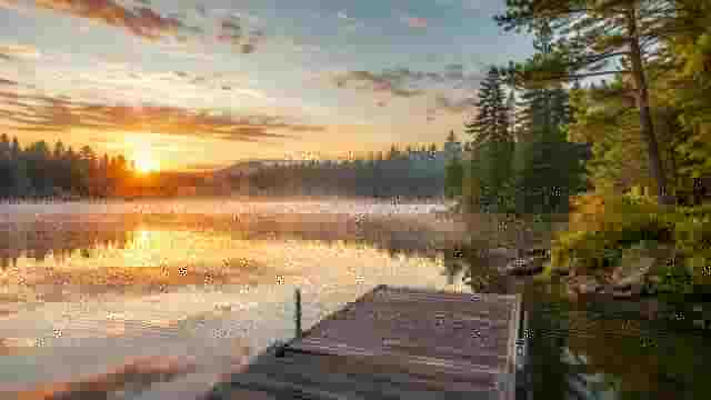 Sunrise over a calm Minnesota lake surrounded by pine forest