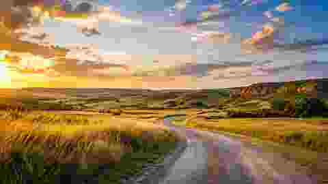 Golden Oklahoma prairie with a winding road at sunset