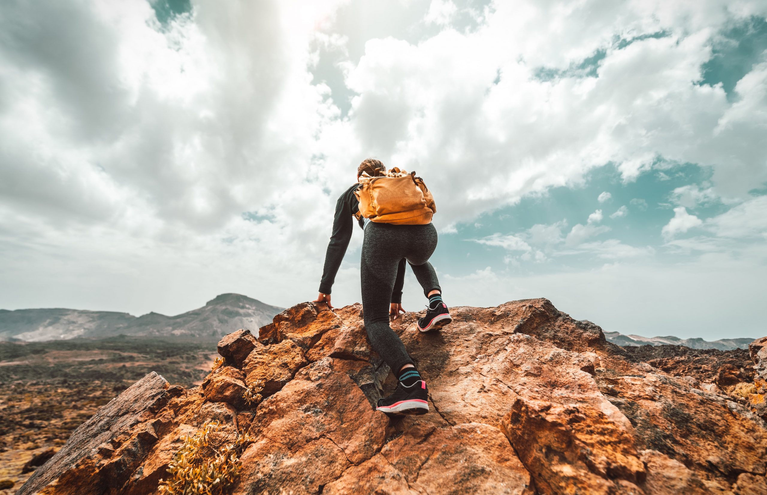 A hiker with a backpack looking across a mountain landscape