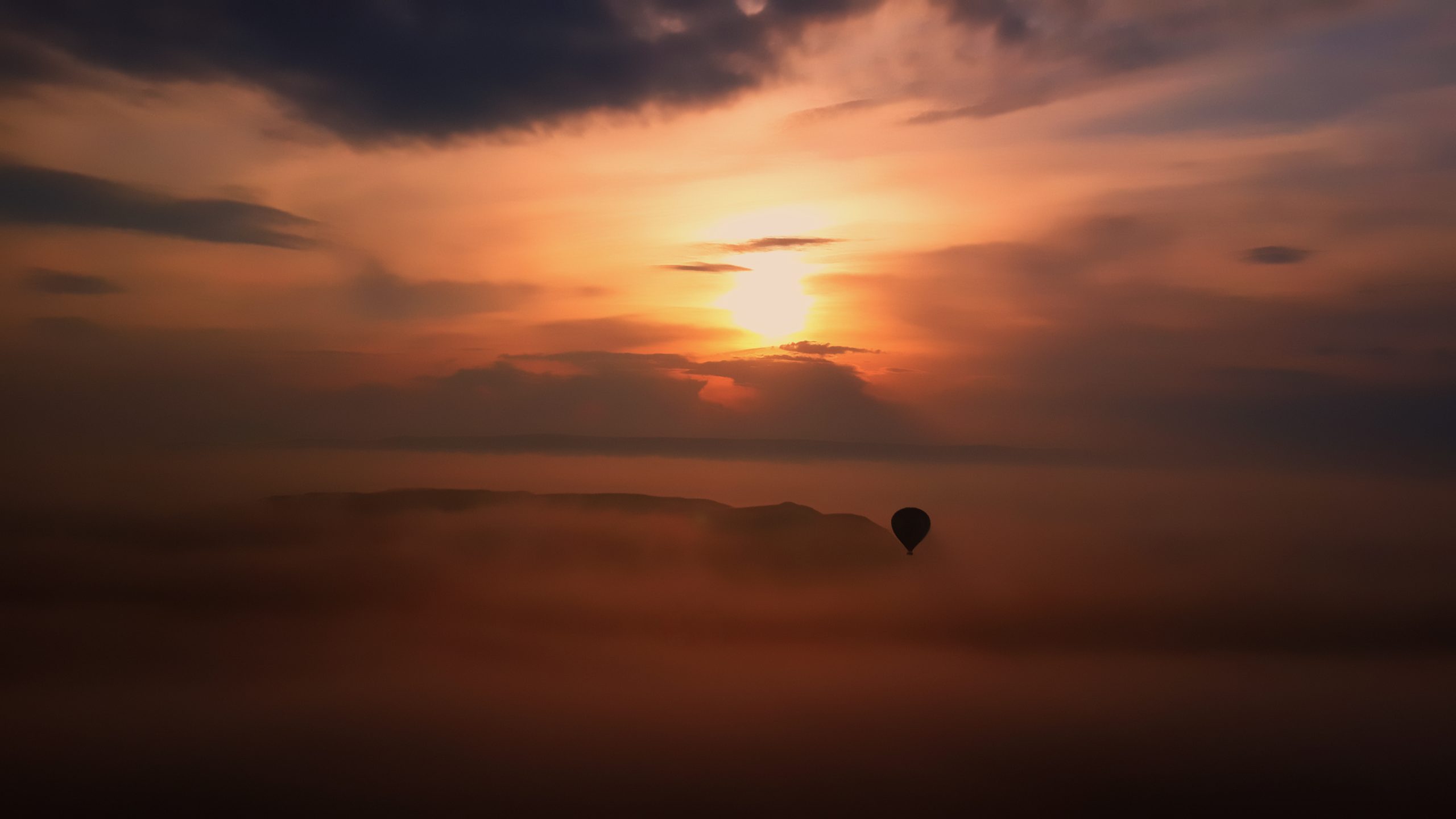A hot-air balloon silhouetted against sunrise over Cappadocia