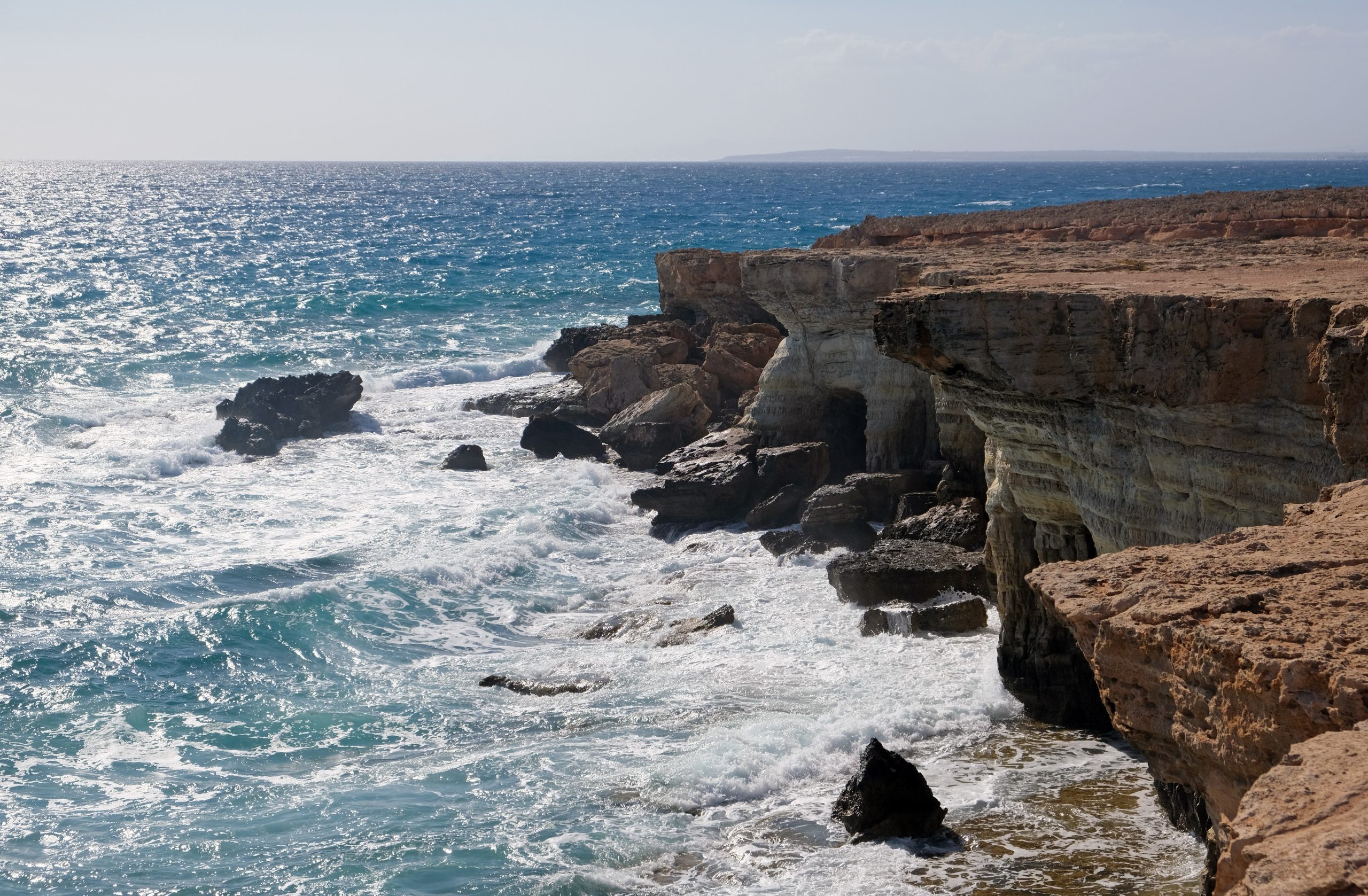 Blue Mediterranean water and waves below the sea caves at Cape Greco, Cyprus