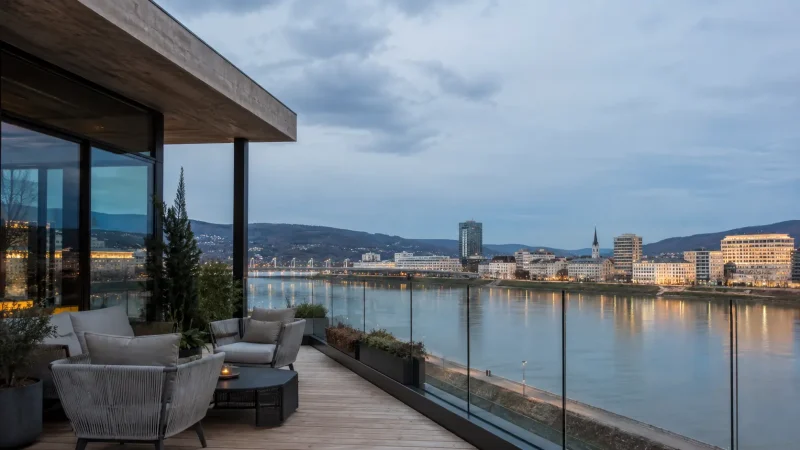 Modern Linz hotel terrace overlooking the Danube riverfront at blue hour