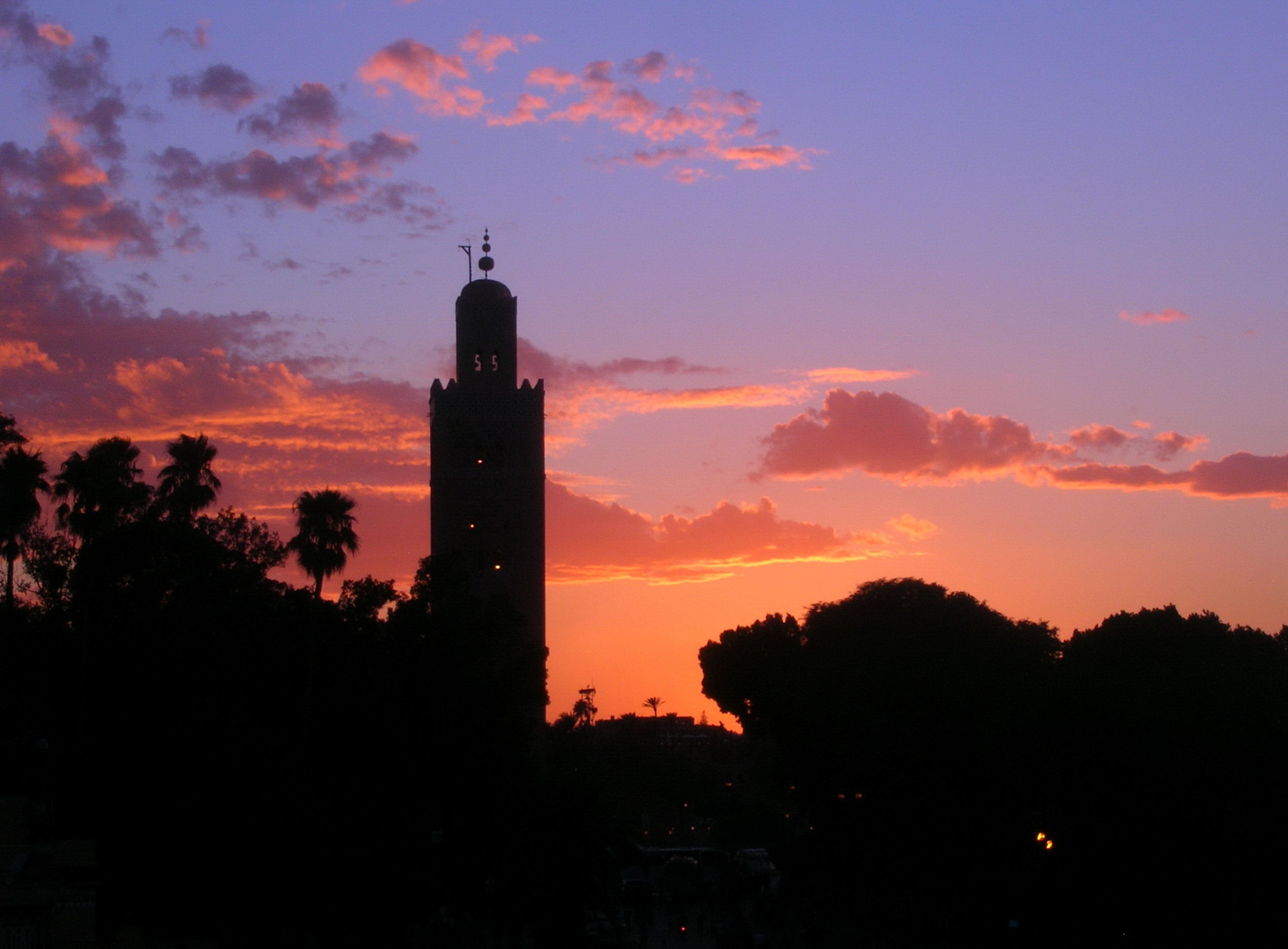 Koutoubia minaret and palm trees silhouetted against a colourful sunset in Marrakech
