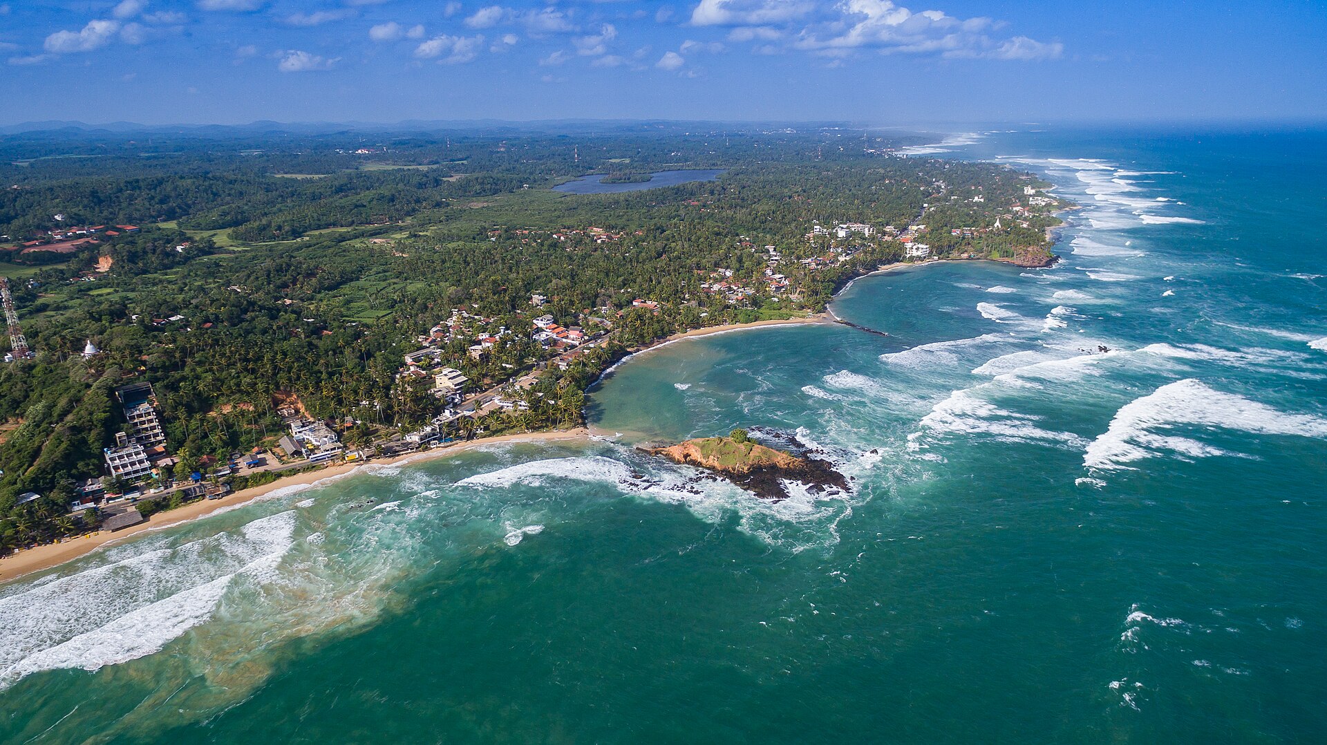 Aerial panorama of Mirissa's palm-lined coastline and Indian Ocean waves